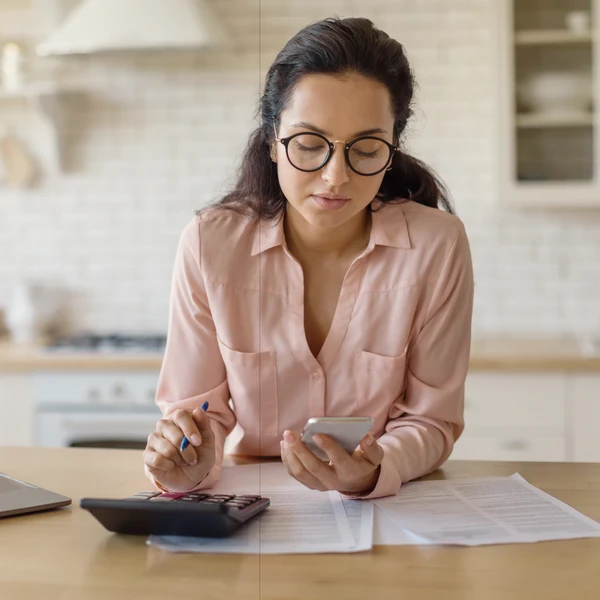 Mujer revisando sus finanzas con una calculadora